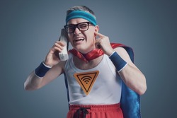 Funny superhero making a phone call using an old obsolete cordless telephone, he can't hear the caller