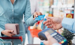 Woman at the supermarket checkout, she is paying using a credit card, shopping and retail concept