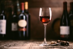 Wine tasting experience in the rustic cellar and wine bar: red wine glass and collection of excellent wines on the background