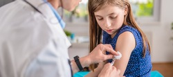 Pediatrics female doctor giving a young girl a vaccine shot in the arm