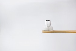 Cavity decayed tooth on wooden brown toothbrush on white background, How to prevent tooth decay and cavities