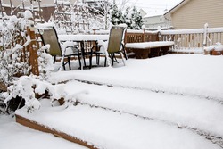 Snowy chairs on garden patio, winter scenery.