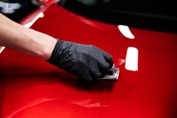Employee of a car wash or car detailing studio applies a ceramic coating