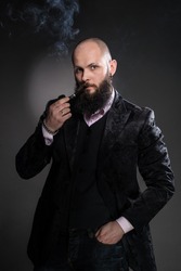 elegant young man is smoking a pipe - gray background