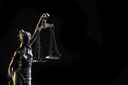 Statuette of the goddess of justice Themis with scales - isolated on black background. Law concept
