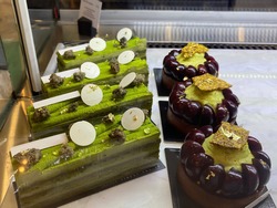 Selective focus of Matcha green tea layer cake topped with crispy red beans and Grape tart in display box