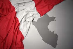 waving colorful national flag of peru on a gray map background.