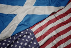 waving colorful flag of united states of america and national flag of scotland.