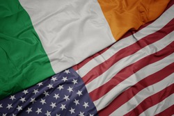 waving colorful flag of united states of america and national flag of ireland.