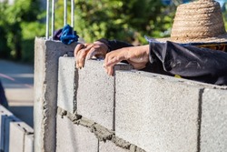 Worker masonry are building walls with cement blocks and mortar by building up in layers.