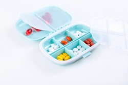 Pill box with colorful pills and vitamins. Plastic blue container with cells for medicines. Health concept. Selective focus, close-up.