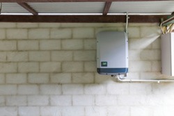 Solar power inverter mounted on brick wall inside garage, domestic system