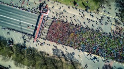 Aerial view from drone on crowd of people who is starting their run on marathon event. Funny shadows on asphalt.