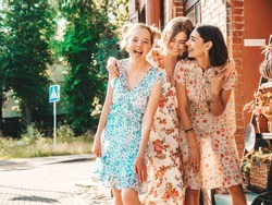 Three young beautiful smiling hipster girls in trendy summer sundress.Sexy carefree women posing on the street background.Models having fun and hugging.Discussing and walking after shopping