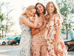 Three young beautiful smiling hipster girls in trendy summer sundress.Sexy carefree women posing on the street background. Positive models having fun and hugging.Walking after shopping