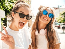 Portrait of two young beautiful smiling hipster female in trendy summer white t-shirt clothes.Sexy carefree women posing on street background. Positive models having fun, hugging and going crazy