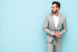 Portrait of handsome confident stylish hipster lambersexual model.Sexy modern man dressed in elegant suit. Fashion male posing in studio near blue wall.