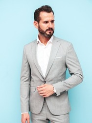 Portrait of handsome confident stylish hipster lambersexual model.Sexy modern man dressed in elegant suit. Fashion male posing in studio near blue wall 