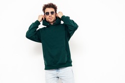 Handsome confident hipster  model.Sexy unshaven man dressed in summer stylish green hoodie clothes. Fashion male with curly hairstyle posing in studio. Isolated on white. In sunglasses