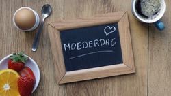 Mother's day written in Dutch on a chalkboard between a breakfast for her