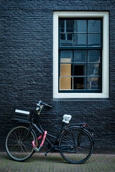 Bicycle parked at house wall in Amsterdam street. Bicycle is a famous very popular means of transport in Netherlands. Amsterdam, Netherlands