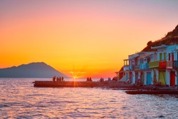 People enjoy scenic sunset in picturesque Klima village above Aegean sea on Milos island in Greece