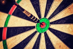 Vintage retro effect filtered hipster style image of   -Success hitting target aim goal achievement concept background - dart in bull's eye close up