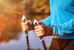 Nordic walking exercise adventure hiking concept - closeup of woman's hand holding nordic walking poles.  With lens flare and light leaks