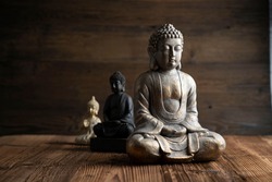 Buddhism concept image. Buddha statue on rustic wooden table.