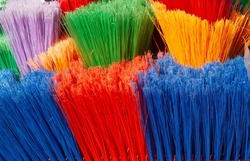 A close up of the multicoloured plastic fibres of brooms awaiting buyers