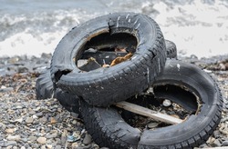 Old tire on the seashore - pollution of nature.