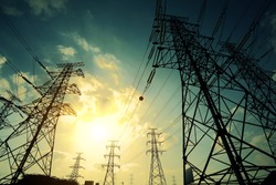 High-voltage power transmission towers in sunset sky background
