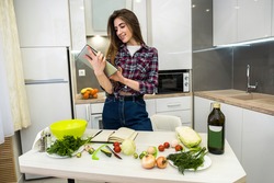 Young woman using a tablet computer to cook different vegetables in her kitchen for everything about healthy nutrition