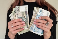 close up of several banknotes denomination of 100 zlotys Polish money zlotys holding a fan in the form of a woman in a suit. The concept of zlotys in women's hands