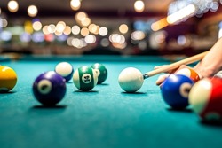 female hand collects colored balls after playing billiards and prepares a new game. Concept of spending free time with games