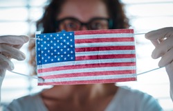 Pandemic Coronavirus. Close up of young woman with surgical mask with the USA flag on it. Concept of Coronavirus, COVID-19, health emergency and quarantine