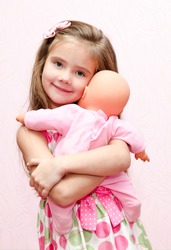 Cute little girl child holding and embracing her doll isolated