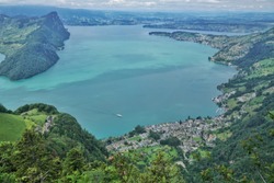 Beautiful green meadows and mountains overlook the turquoise waters of Switzerland’s lake Lucerne, Vitznau town nestles on the bank.