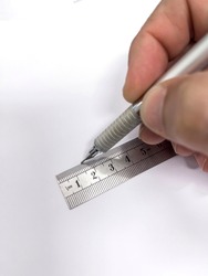 hand with a metal mechanical pencil making a straight line with a metallic millimeter ruler on a blank sheet of paper, selective focus in the ruler, vertical