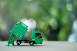 Miniature green plastic garbage truck. Children toy. Garbage truck toy
