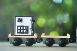 Miniature toy train carrying safe box. Concept of protect and move money