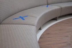 Waiting sofa with symbol on seat for the social distancing during the Covid-19 pandemic with special warning signs
