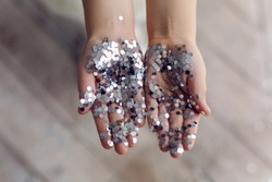 hands of a little girl holding silver sequins