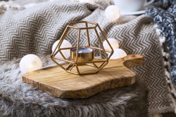 Home deco indoor with candle holder and light bulbs, cozy blanket and faux fur,cozy winter interior details 