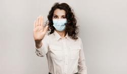 Masked woman makes stopping hand gesture. Influencer Girl blogger in medical mask talks about covid-19, coronavirus. Girl in medical mask stops 2019-nCov