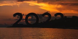Concept of New 2022 growth and development prospects. Silhouette digits 2022 from behind the mountains with sunset background. Success new year concept. Silhouette with happy new year numbers