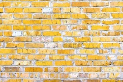 Brick wall with unusual yellow bricks made of whole yellow bricks and broken yellow bricks for an abstract yellow background