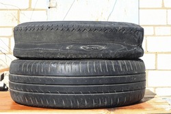 old worn out summer tire next to another old summer tire as sample of damaged summer tires from two summer tires