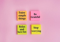 Enjoy simple things ,  be grateful, relax ,have fun ,stop worrying  words  written on sticky notes on pink background .Positive thinking 
 , motivational concept