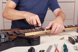 Guitar master crowning frets on the guitar neck with fret files.